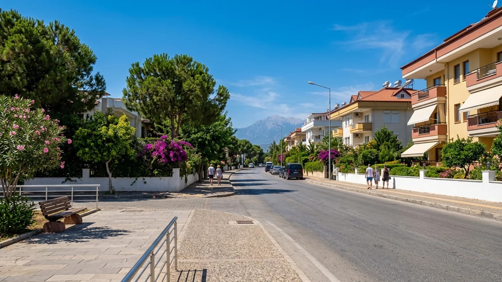Eine ruhige, von Bäumen gesäumte Allee im Osten Antalyas mit modernen Gebäuden, Bougainvillea und fernen Taurusbergen.
