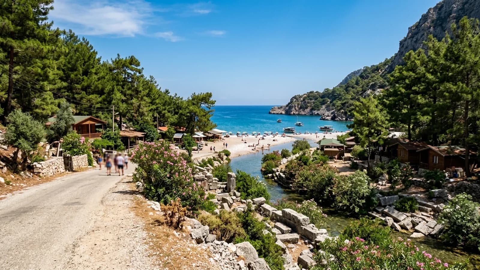Olimpos çakıl plajına açılan ormanlık vadideki ahşap bungalovlar ve akarsu kenarındaki antik taşlar.