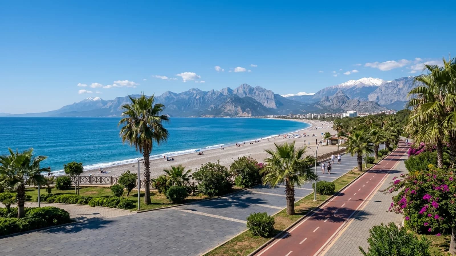 Konyaaltı beach and seafront park, Antalya Curving pebble beach with a green seafront park, palm trees and cycle path, backed by steep mountains.