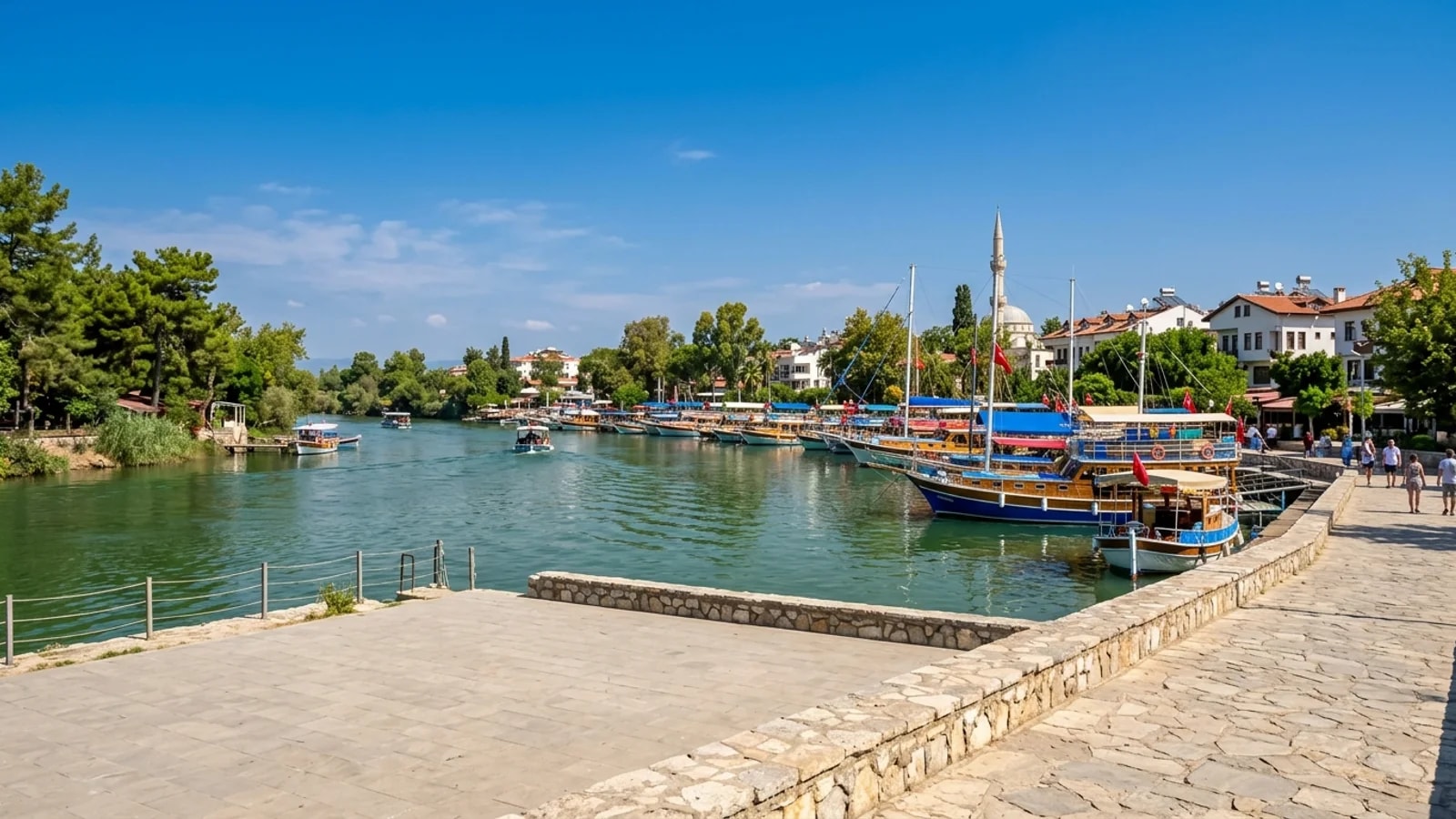 Manavgat Nehri ve geleneksel ahşap tekneler Yeşil Manavgat Nehri kıyısında ağaçların arasında demirlemiş renkli ahşap tekneler yavaş akan suda süzülüyor.