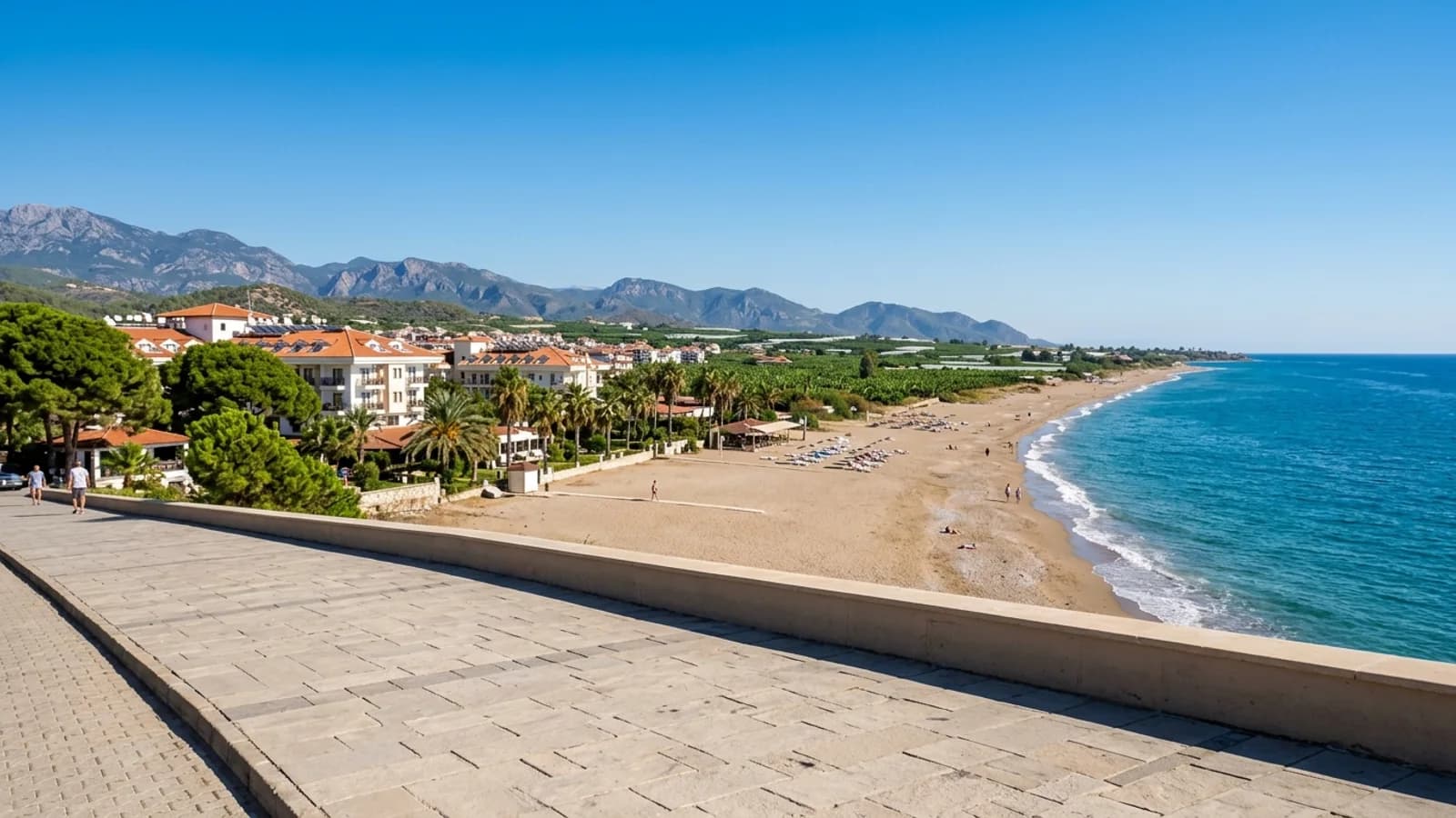 Strandresort Kızılağaç nabij Antalya Een zandstrand in Kızılağaç met resorthotels, groene plantages en bergen in de verte.
