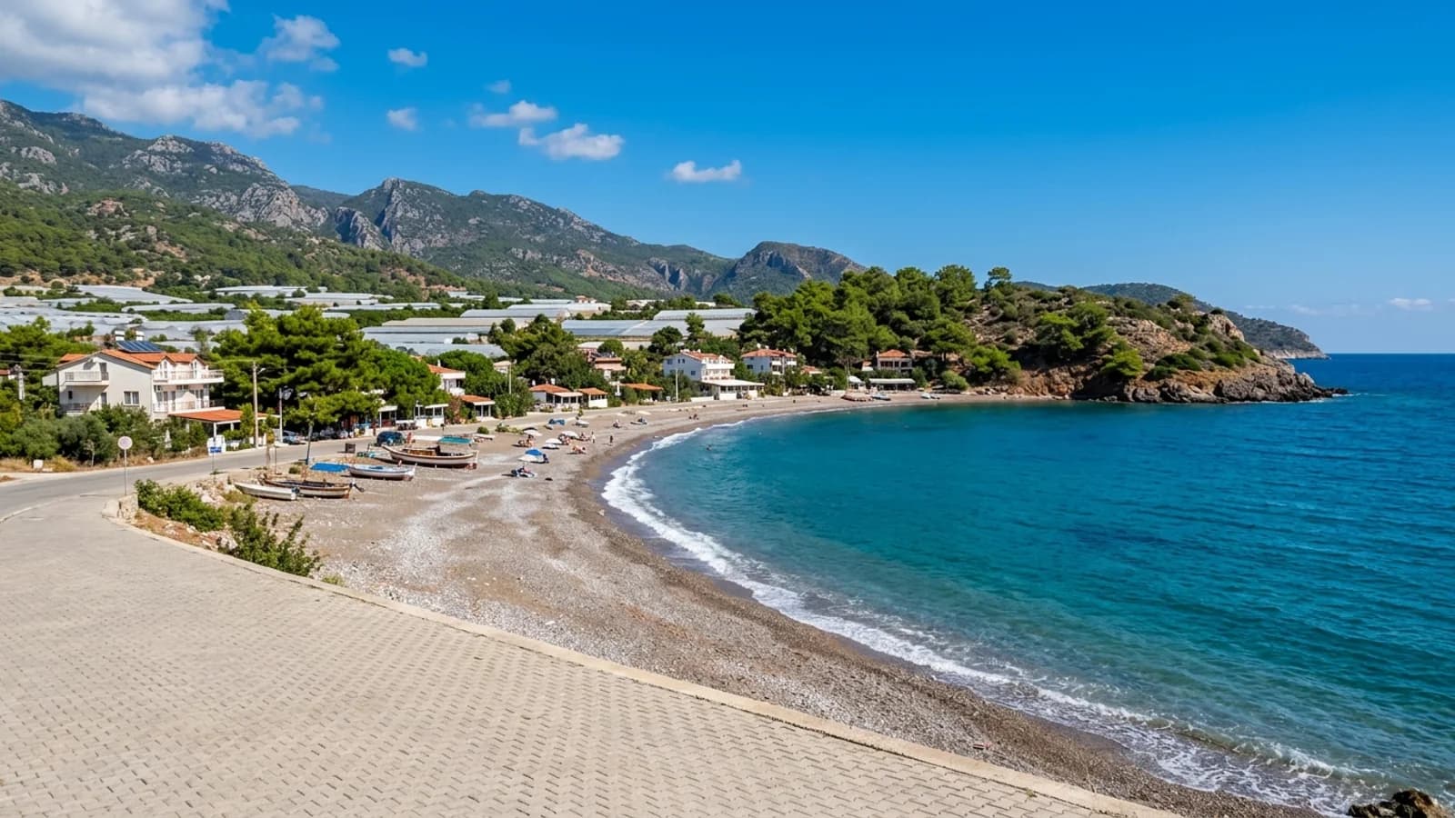 De baai van Mavikent nabij Antalya. Een kleine baai in Mavikent met een kiezelstrand, lage pensions en kassen op het vlakke land.